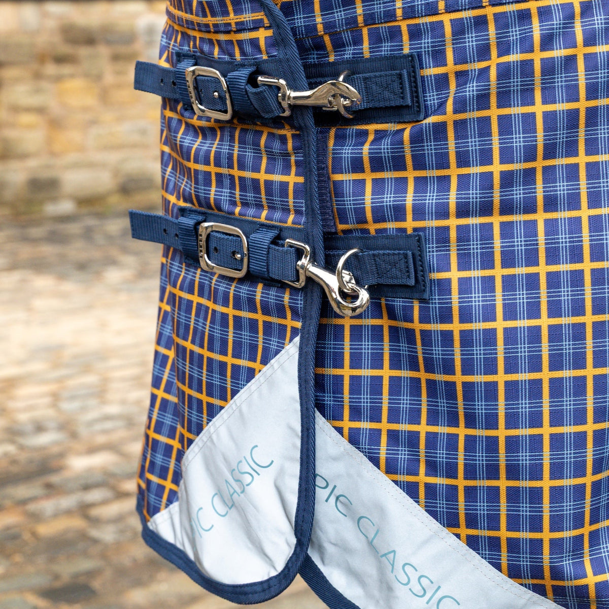 Close-up of a blue and yellow plaid horse blanket with a brand logo.