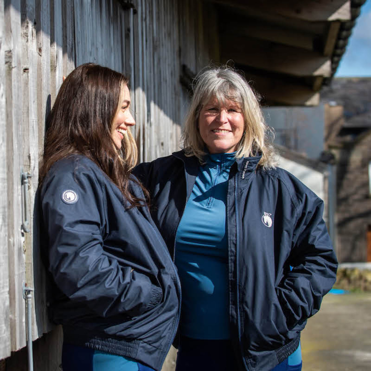 Two adults wearing unisex black waterproof jackets with fleece lining, standing outdoors.