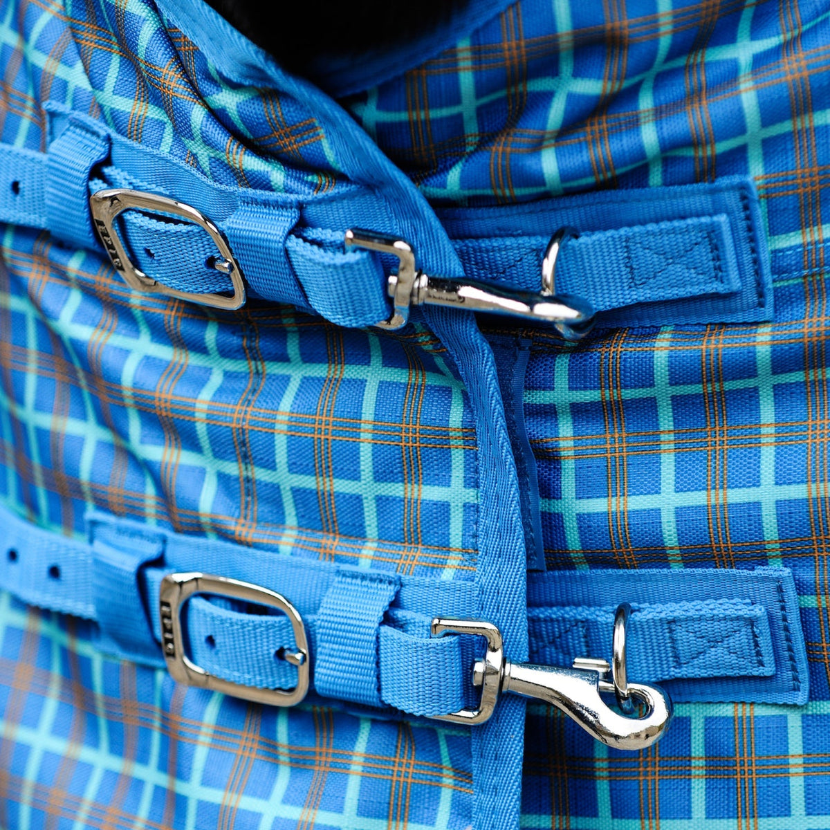 Close-up of a blue plaid bag with straps and buckles.