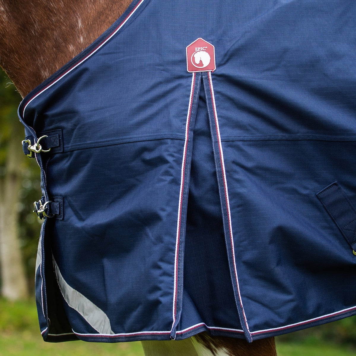 Navy horse blanket with a red brand logo on a horse in a field