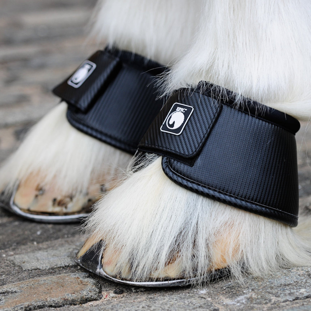 Black protective leg wraps on a horse's legs with a brand logo.